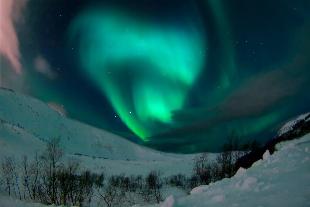 Aurore Boréale Aurore Boréale de couleur verte et rose au-dessus d'un paysage enneigé