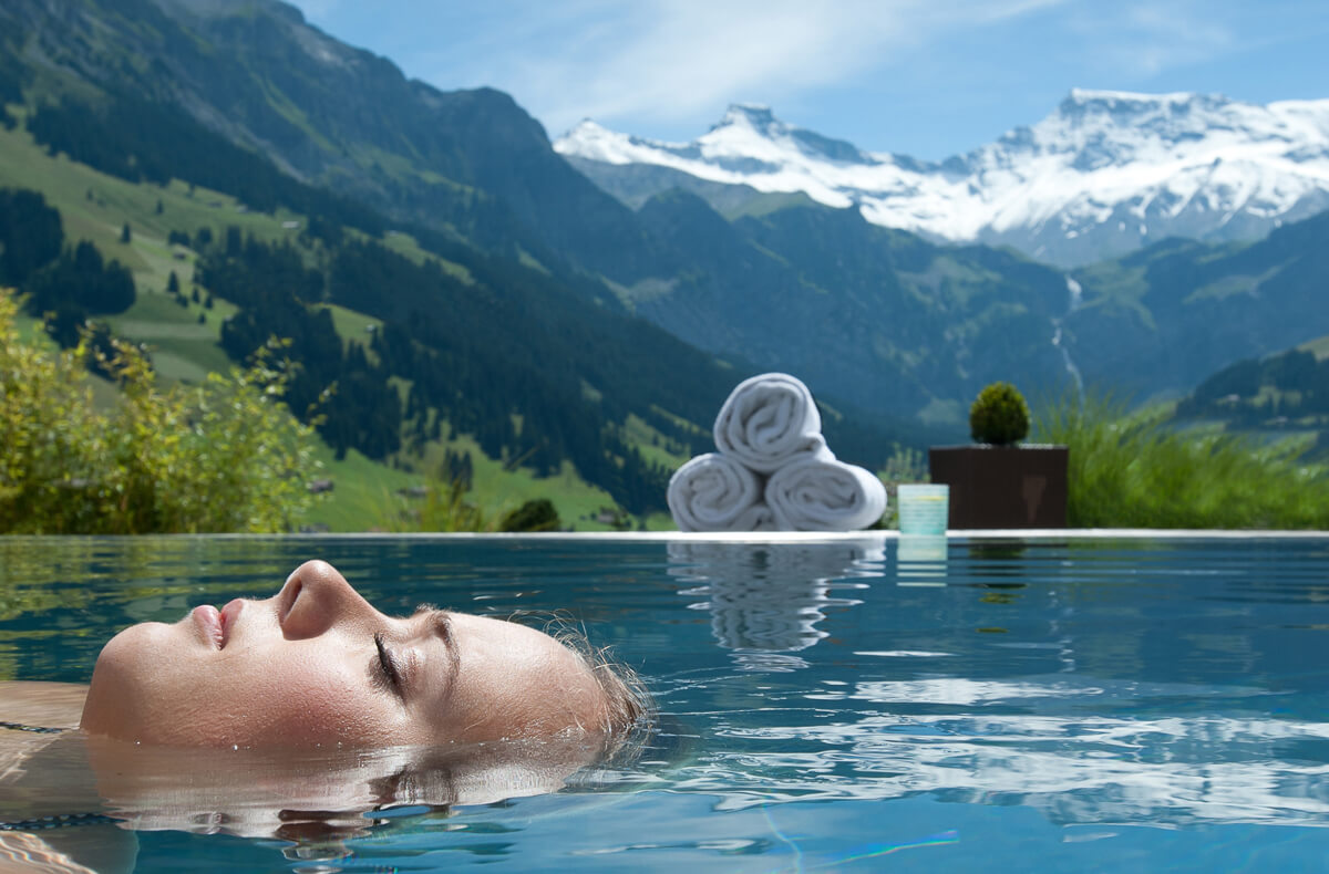 Frau schwimmt im Infinity-Pool des The Cambrian Hotel Adelboden in Bern in der Schweiz.