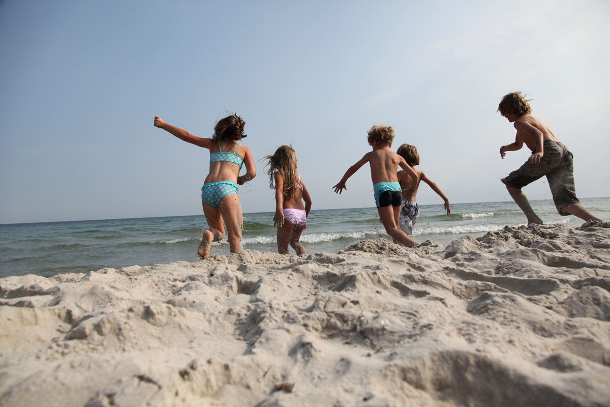 Kinder toben am Strand im Sand.